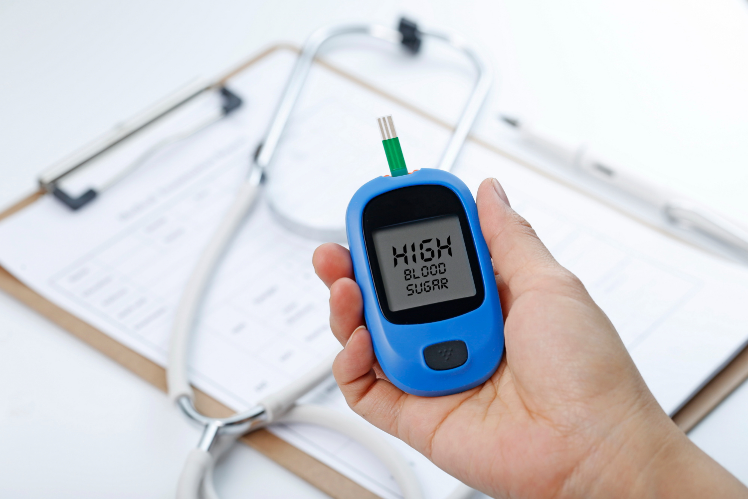 Hand holding a blood glucose meter measuring blood sugar