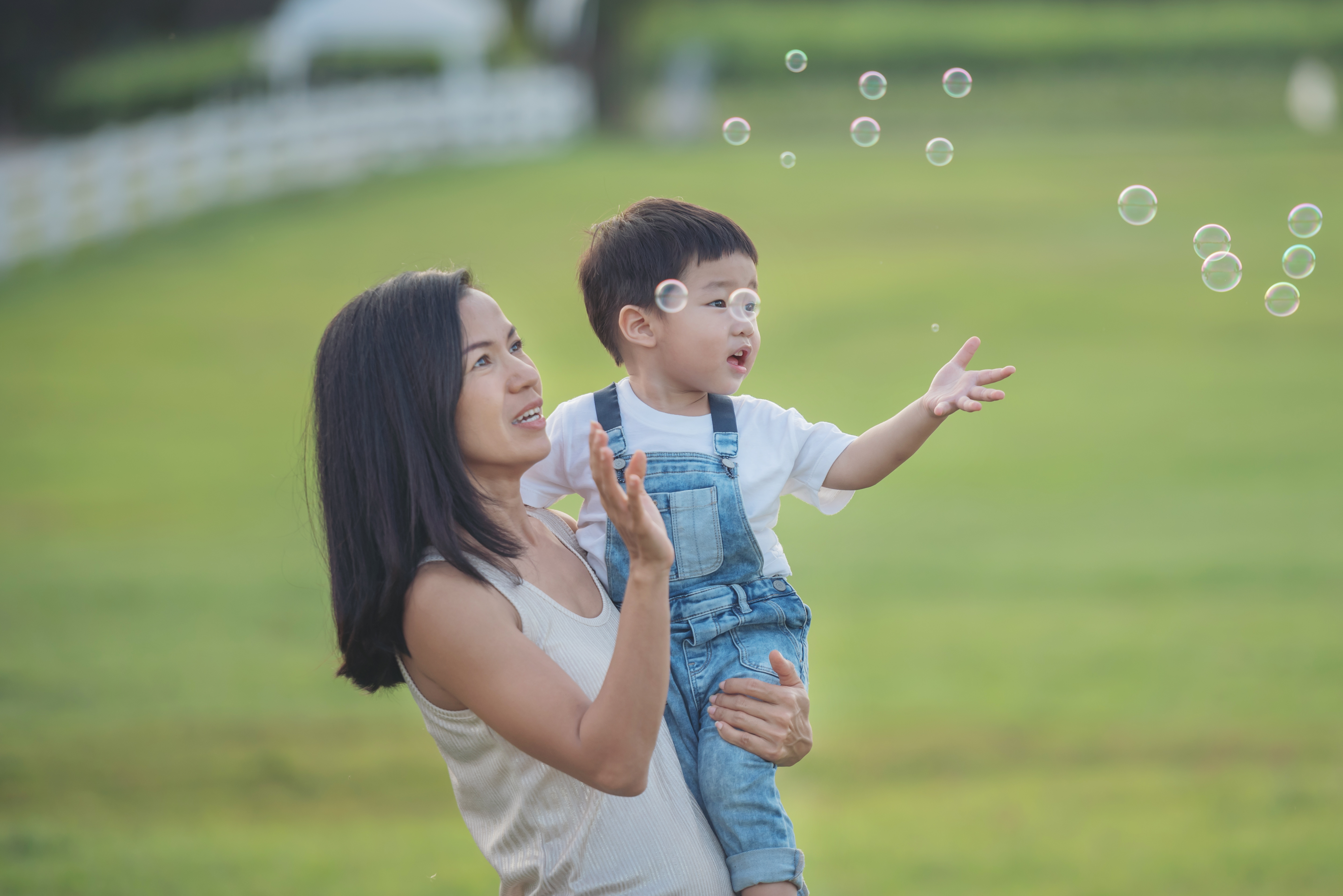 asian mum blowing bubble with her baby outdoor