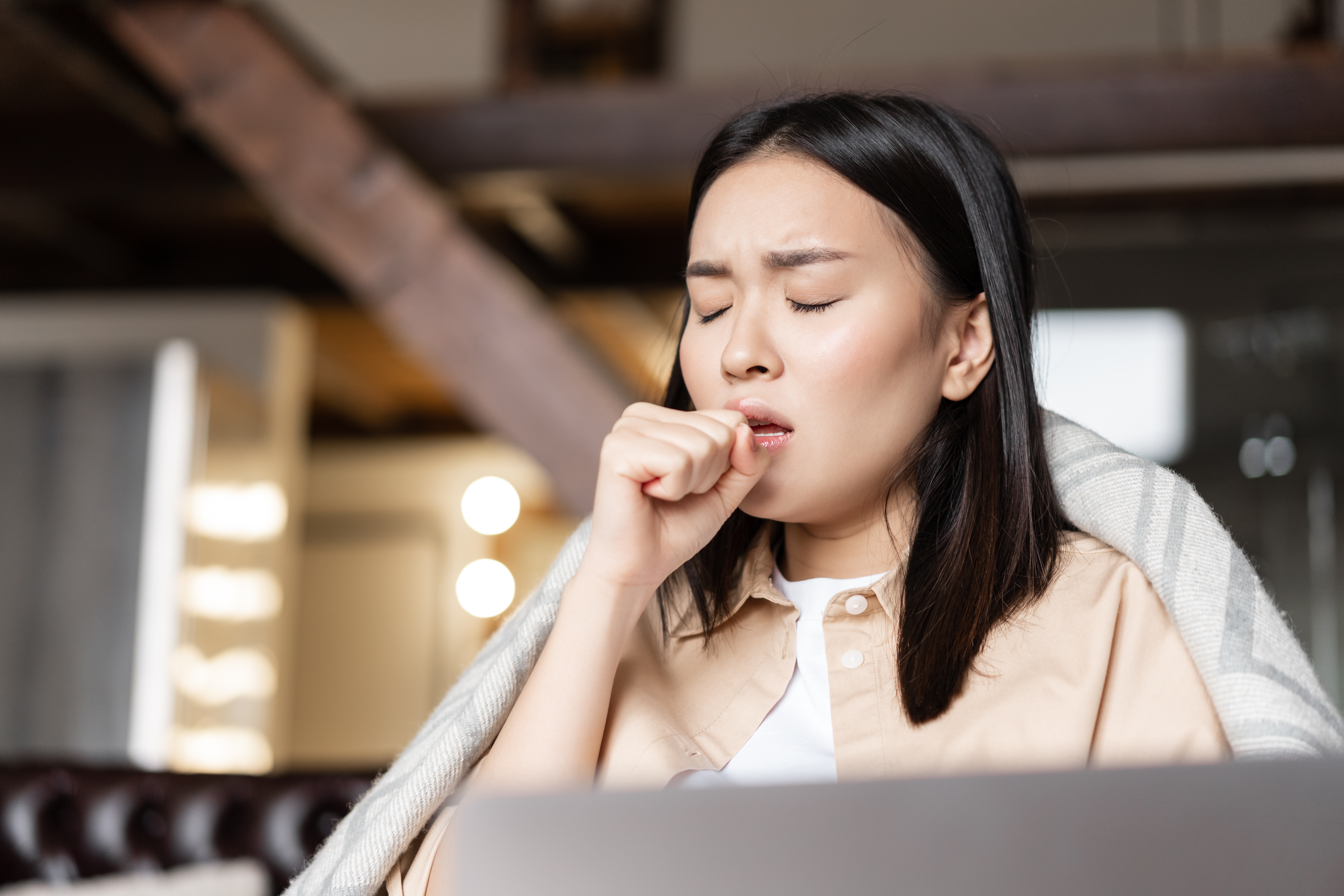 asian woman coughing covering mouth outdoors