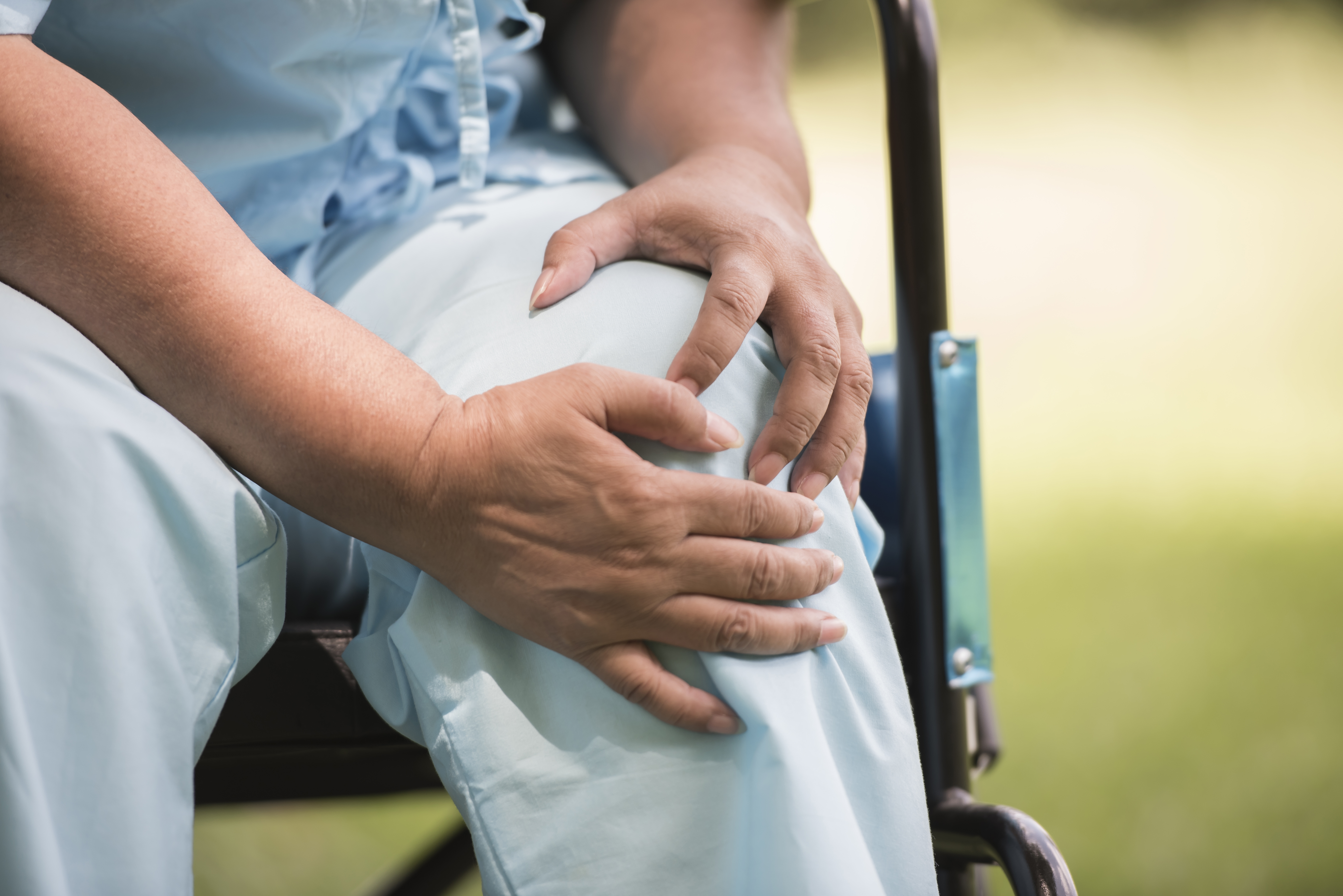 elderly women sitting on wheelchair having knee pain