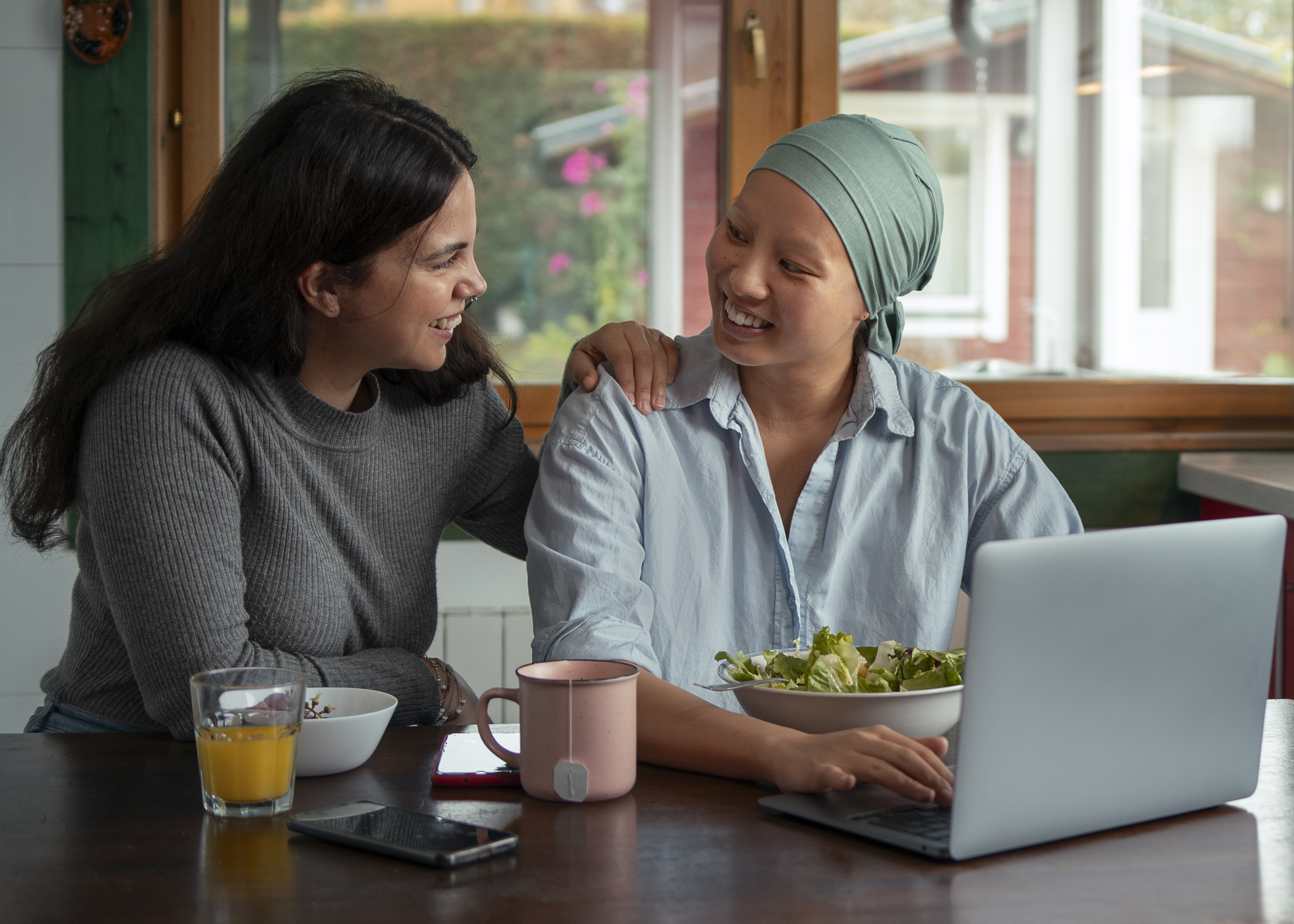 woman with cancer using laptop with friend