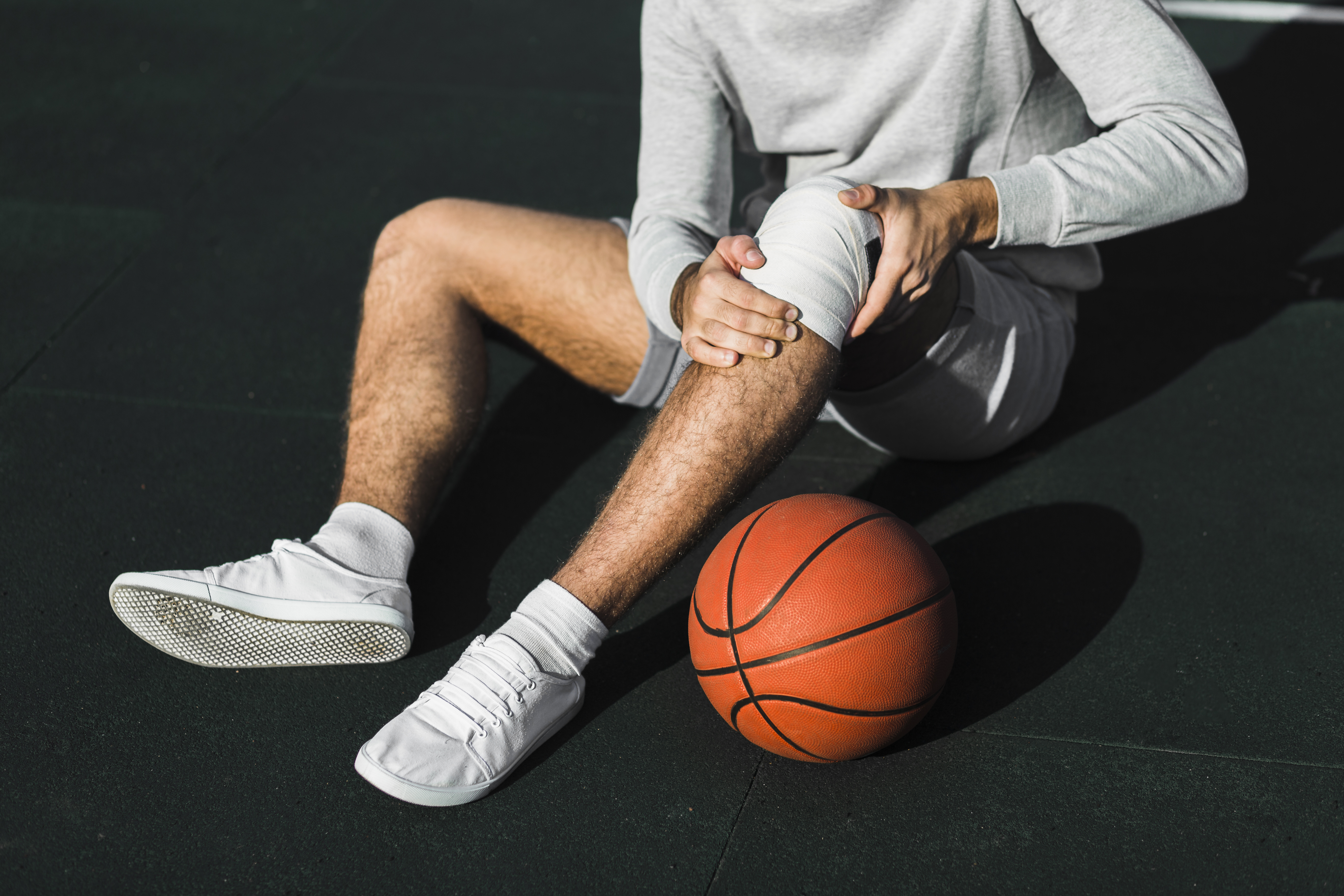 basketball player sitting on floor having knee injury
