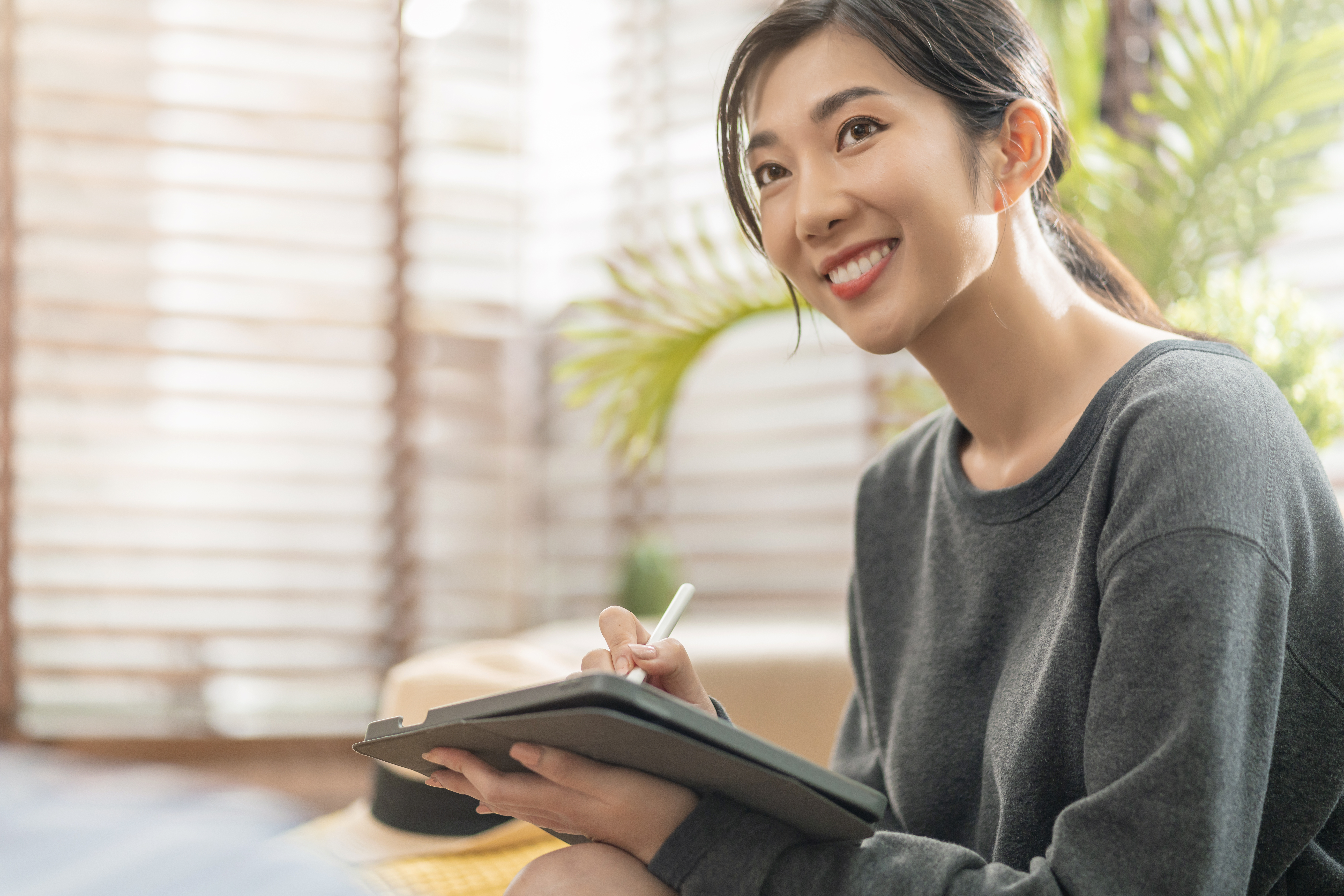 young asian woman doing homework and smilling
